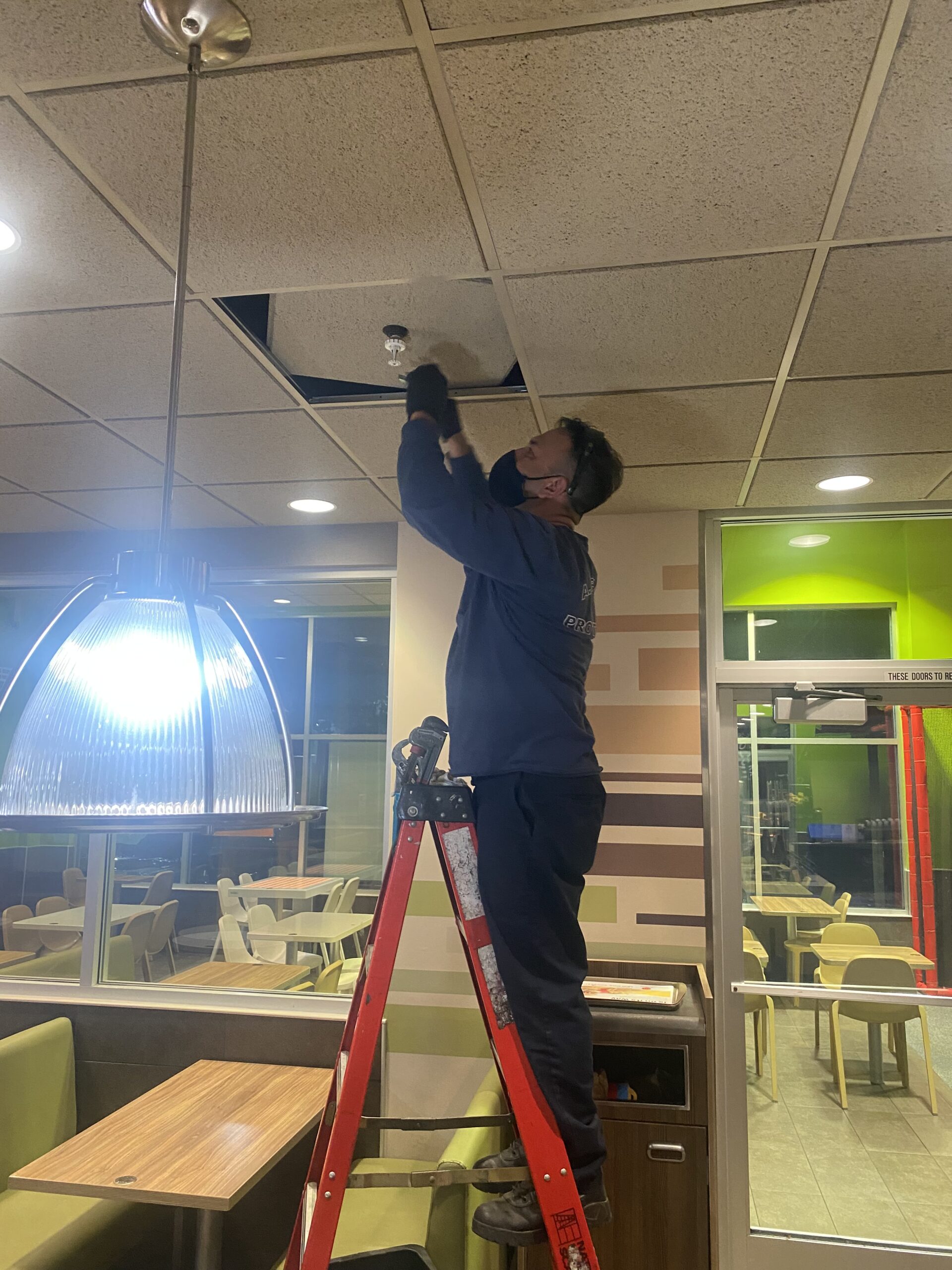 Technician Performing Fire Sprinkler Maintenance on Ceiling System